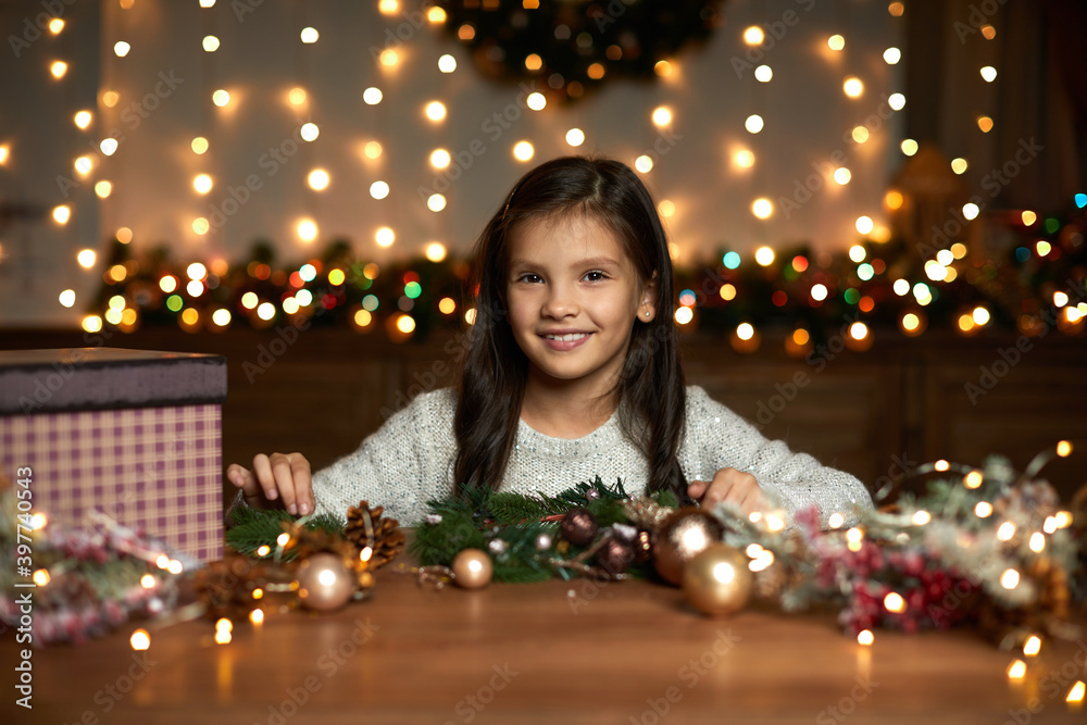 happy cute little child girl makes a handmade Christmas wreath at home. happy cute little child girl makes a handmade Christmas wreath at home.