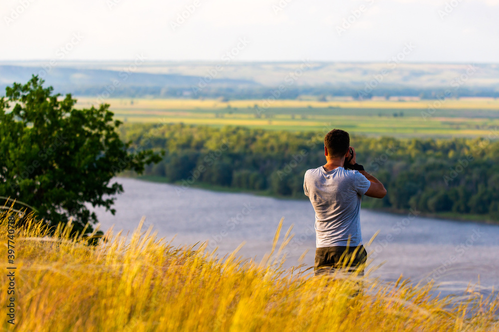 Back view of a photographer taking pictures of river landscape