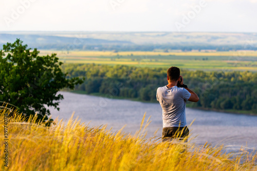 Back view of a photographer taking pictures of river landscape