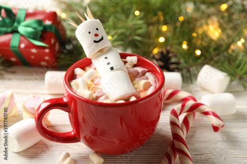 Cup with snowman marshmallow on Christmas wooden background