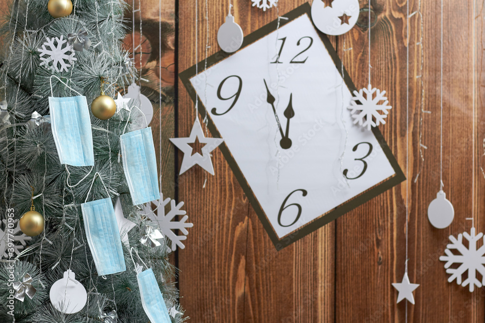 face masks hang on a Christmas tree, on a wooden clock background. Pandemic. face masks hang on a Christmas tree, on a wooden clock background. Pandemic.