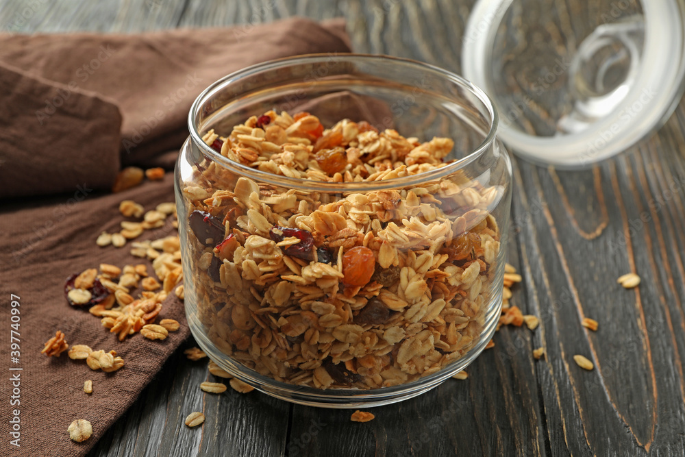 Glass jar with tasty granola on wooden background Glass jar with tasty granola on wooden background
