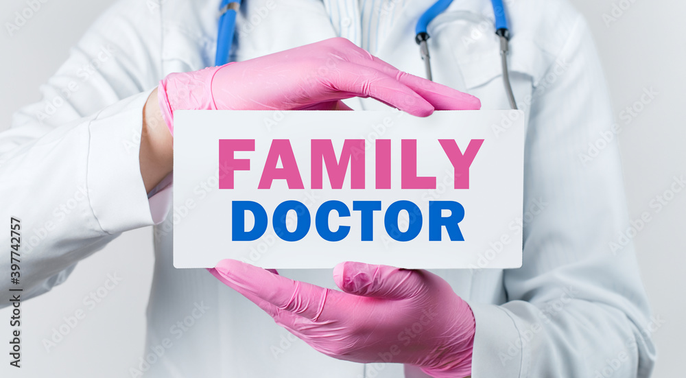 Cropped view of female doctor in a white coat and pink sterile gloves holding a card with words - FAMILY DOCTOR Cropped view of female doctor in a white coat and pink sterile gloves holding a card with words - FAMILY DOCTOR