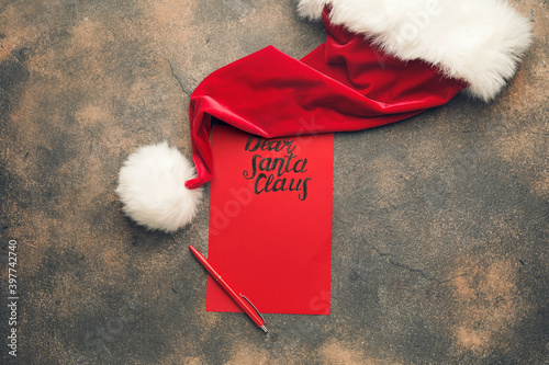 Blank letter to Santa and hat on grunge background