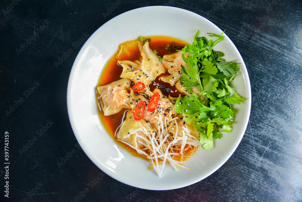 Boiled meat dumplings with fresh parsley, soy sauce and sesame seeds. Delicious meal for dinner.