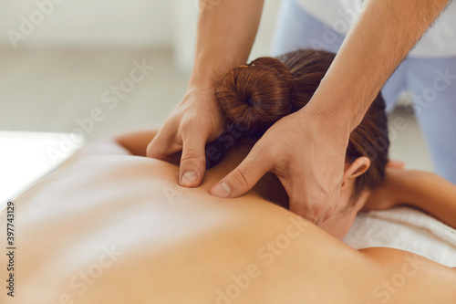 Young woman enjoying relaxing remedial body massage done by professional masseur photo