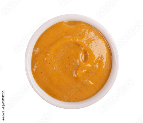 Mustard sauce in bowl, isolated on white background. Honey mustard salad dressing. Top view.