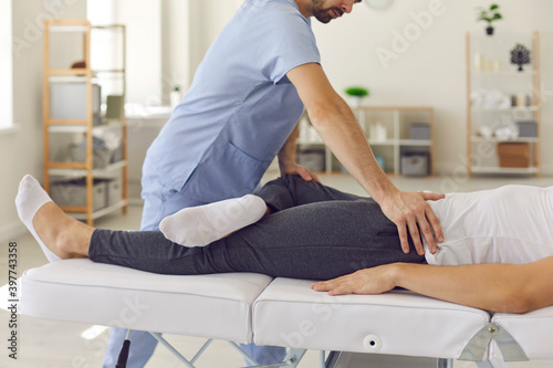 Confident man professional doctor osteopath fixing man patinets legs in position to fix joints