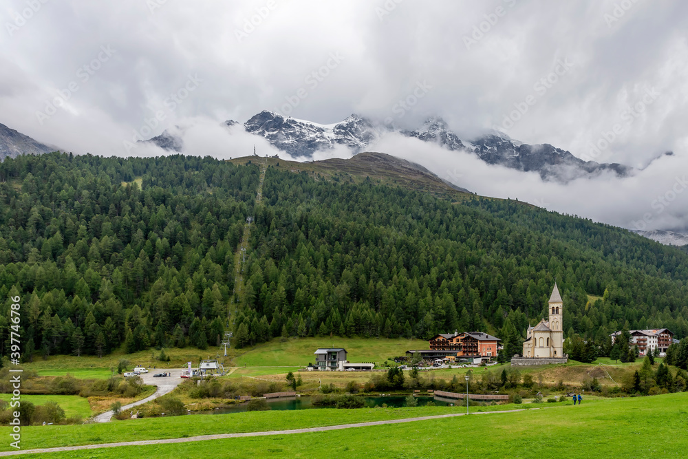 Panoramic view of Solda, South Tyrol, Italy, its parish church on the lake, with the Ortler mountains in the background