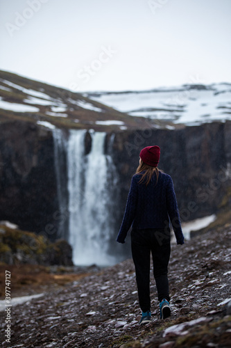 A woman walking towards a waterfall in Iceland in winter