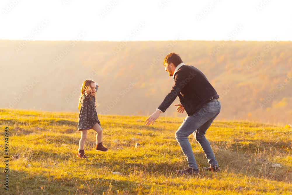 Family time. Photo of cute little girl running in dad direction to catch her, dad standing with rised hands.
