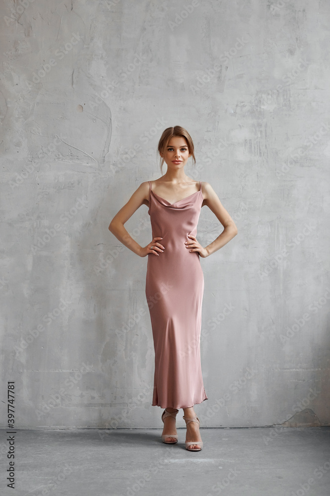 Fototapeta premium Beautiful sexy woman in a light beige silk dress. Noise, out of focus