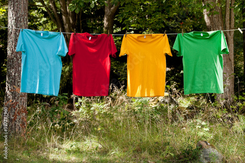 Four colorful t shirts hanging on a clothesline, drying out in the nature.