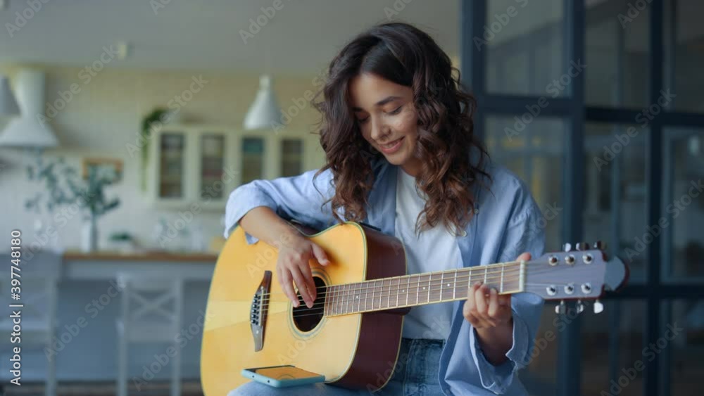 Girl playing guitar. Female guitarist recording guitar sound on mobile phone