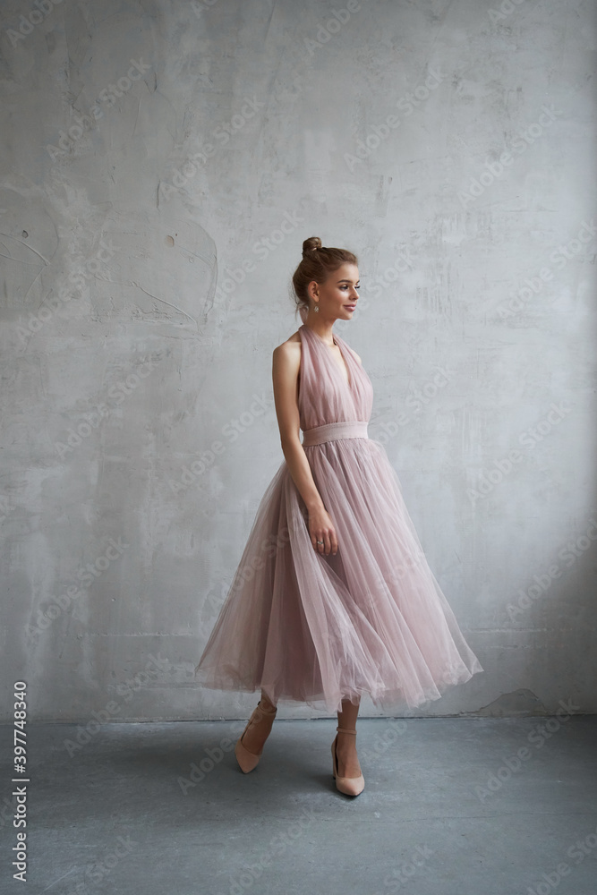 Sexy Fashion beautiful woman in dress is standing against the wall. Perfect makeup, romantic portrait of a blonde woman Sexy Fashion beautiful woman in dress is standing against the wall. Perfect makeup, romantic portrait of a blonde woman