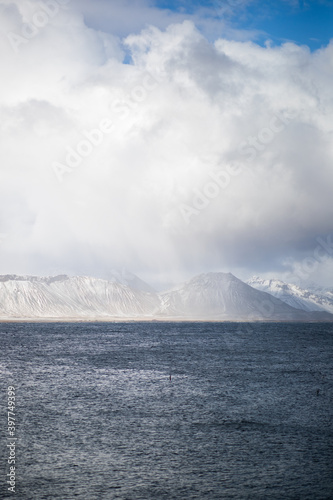 Landscape of snowy mountains and sea in Iceland on a cloudy day