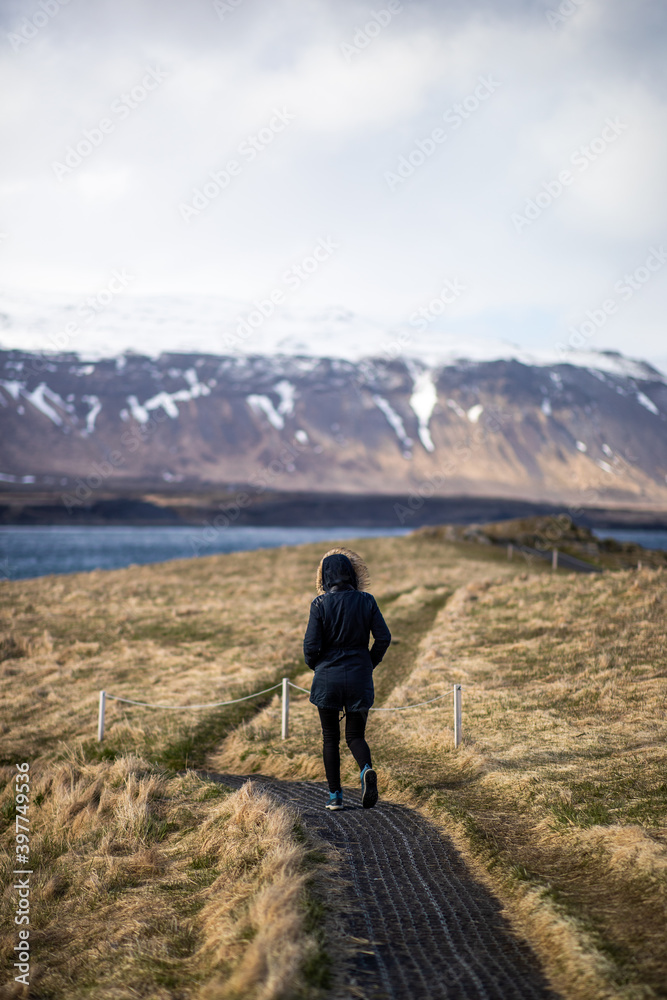 A woman walking on a path towards mountains in Iceland