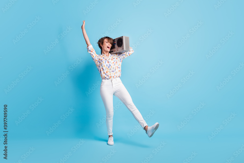 Fototapeta premium Full length photo of young excited woman crazy have fun enjoy discotheque hold boombox isolated over blue color background