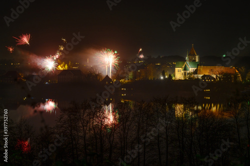 New Year fireworks at the Ratzeburg cathedral with reflections in the lake at night, copy space in the dark sky
