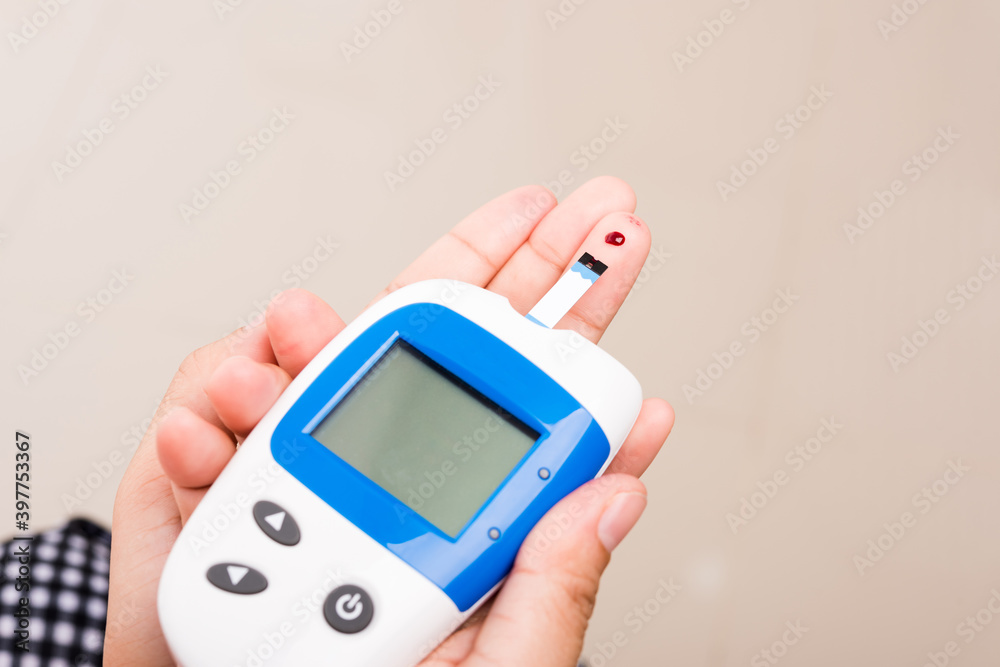 Closeup Hands woman measuring glucose test level check with blood on finger by glucometer at home she monitor and control high blood sugar diabetes and glycemic health care concept Closeup Hands woman measuring glucose test level check with blood on finger by glucometer at home she monitor and control high blood sugar diabetes and glycemic health care concept