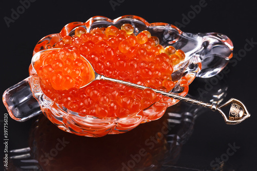 red caviar in a glass dish with a silver spoon