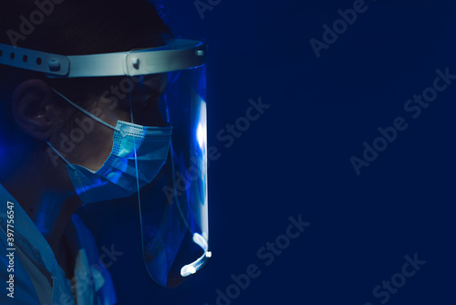 woman doctor with face shield and mask side view on dark blue background