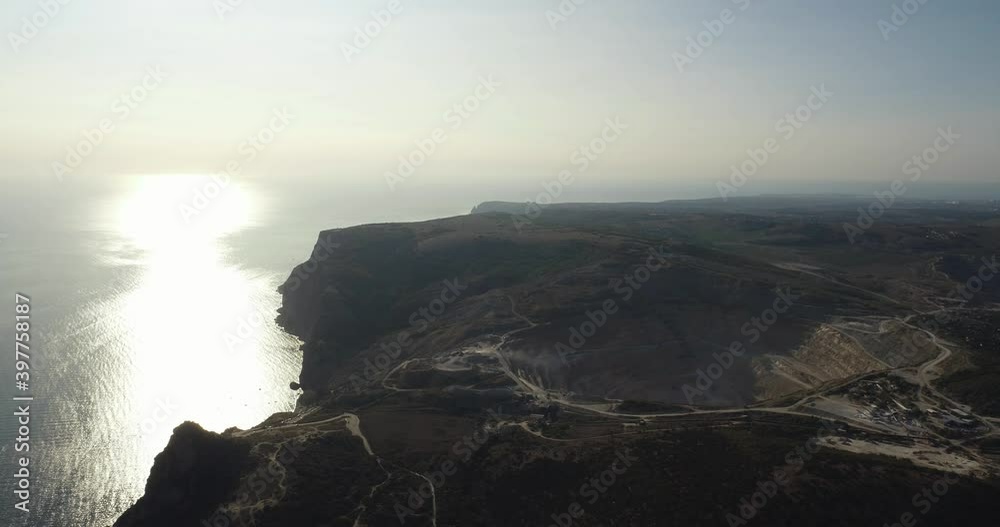 Industrial of opencast mining quarry with a lots of machinery at work on sea rocky coast. Extraction of gold, copper. Aerial drone wide shot at summer sunny sunset Industrial of opencast mining quarry with a lots of machinery at work on sea rocky coast. Extraction of gold, copper. Aerial drone wide shot at summer sunny sunset