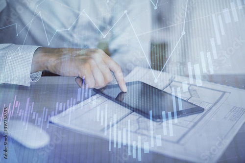 Double exposure of man's hands holding and using a digital device and forex graph drawing. Financial market concept.