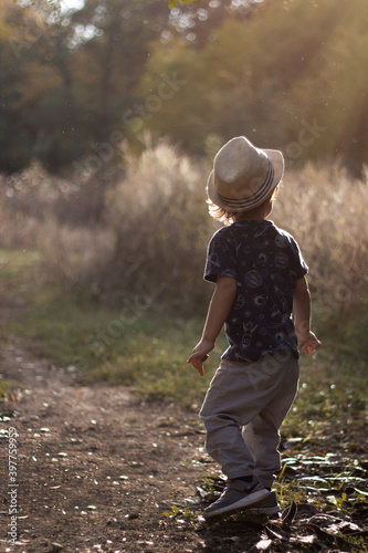 Stylish, happy child walks in the summer park in a straw hat