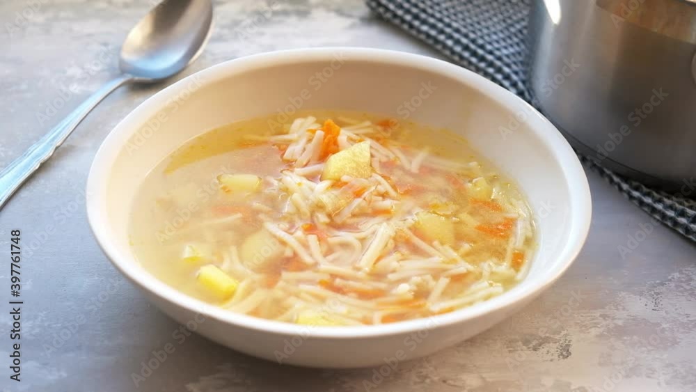 Chicken noodle soup with vegetables in a white plate. Comfort food concept. Chicken noodle soup with vegetables in a white plate. Comfort food concept.