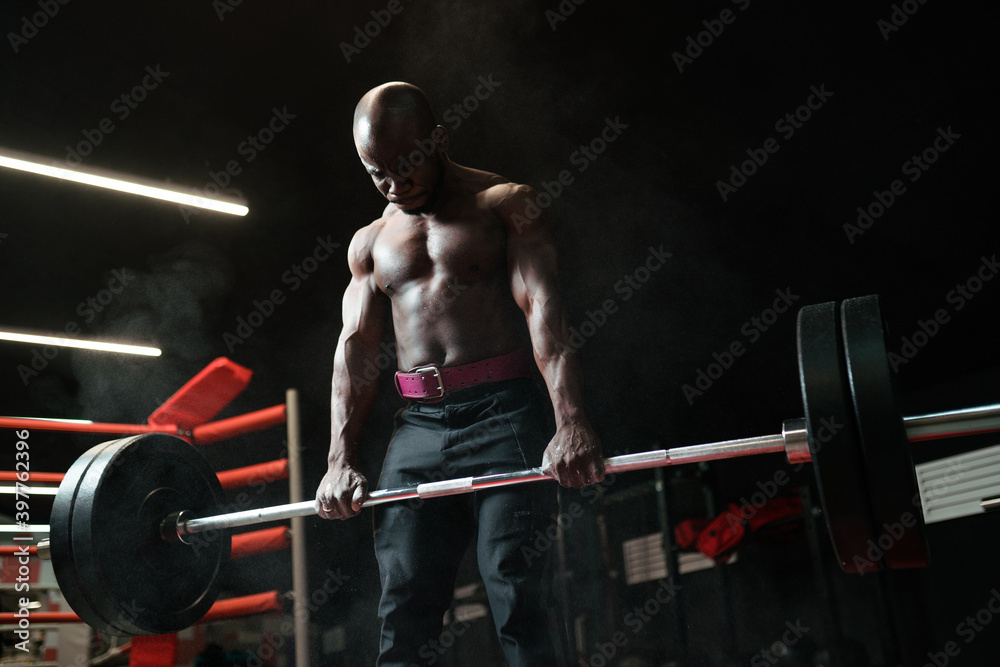 Muscular african american man weightlifter or bodybuilder doing exercises with a barbell in the gym Muscular african american man weightlifter or bodybuilder doing exercises with a barbell in the gym