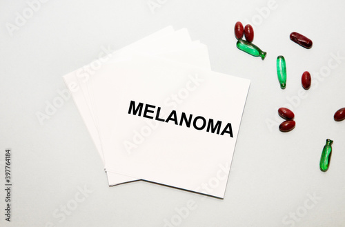 On the sheet for notes the text of MELANOMA, next to red and helen capsules.