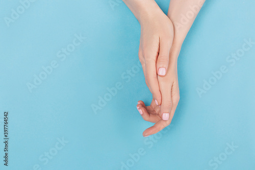 Manicure and nail care concept. Two woman hands with perfect pastel pink nail polish on aqua blue background. Summer minimal manicure. Flat lay, top view. Copy space.