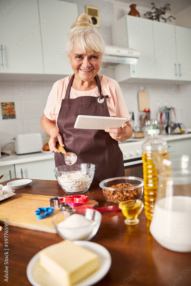 Friendly aging woman preparing for baking process
