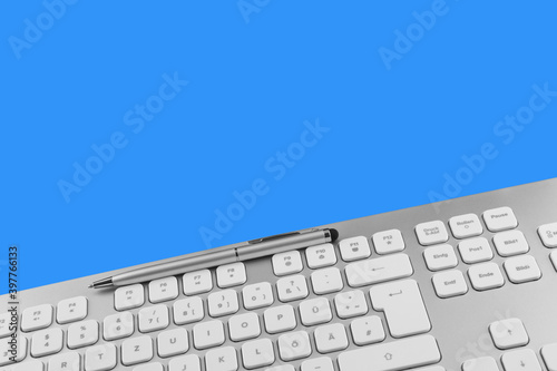 PC keyboard and pen against blue background photo