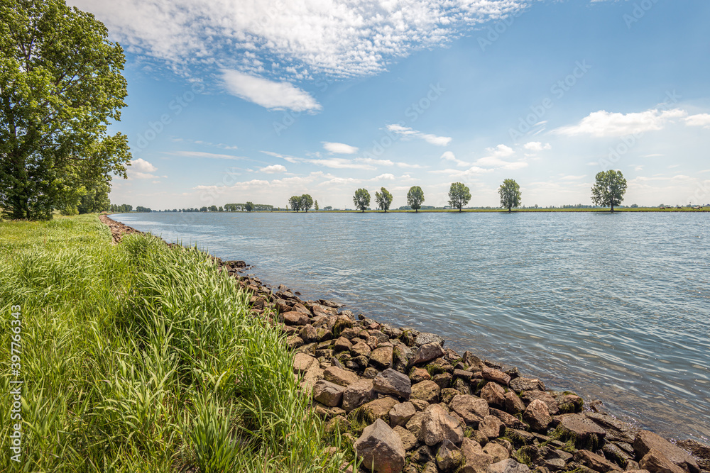 Stones on the banks of a Dutch river provide protection against erosion. The photo was taken in the spring season at the Bergsche Maas river in the province of Noord-Brabant.