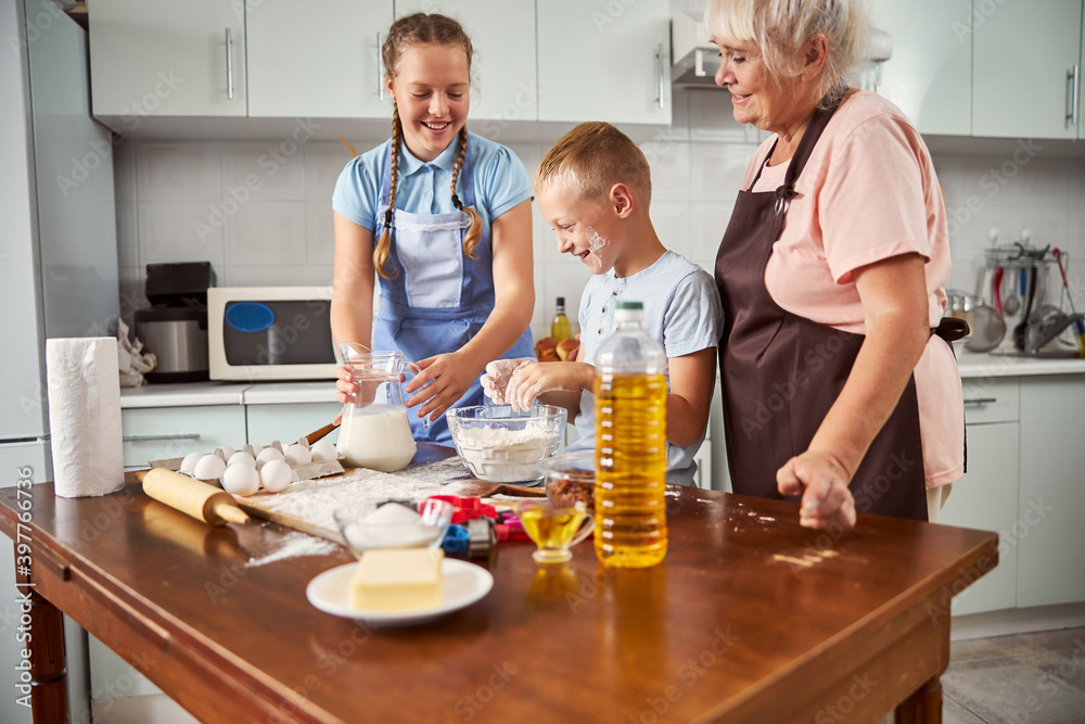 Brother and sister cooking with their grandma in kitchen