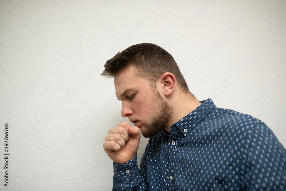 a young caucasian businessman coughs into his hand and wears a mask against the corona virus. corona virus infection a young caucasian businessman coughs into his hand and wears a mask against the corona virus. corona virus infection