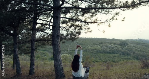a girl lies down and holds her laptop in her arms in the park.