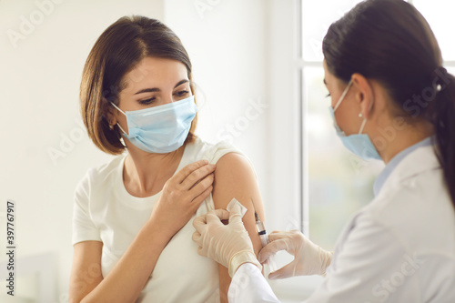 Young patient in a medical face mask getting an antiviral vaccine at the hospital photo