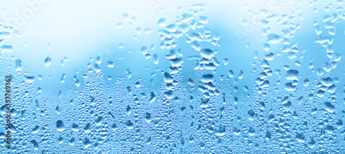 Water drops on glass. Blue abstract wall background.