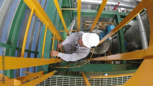 Worker climbing on vertical ladder  in petroleum refinery plant