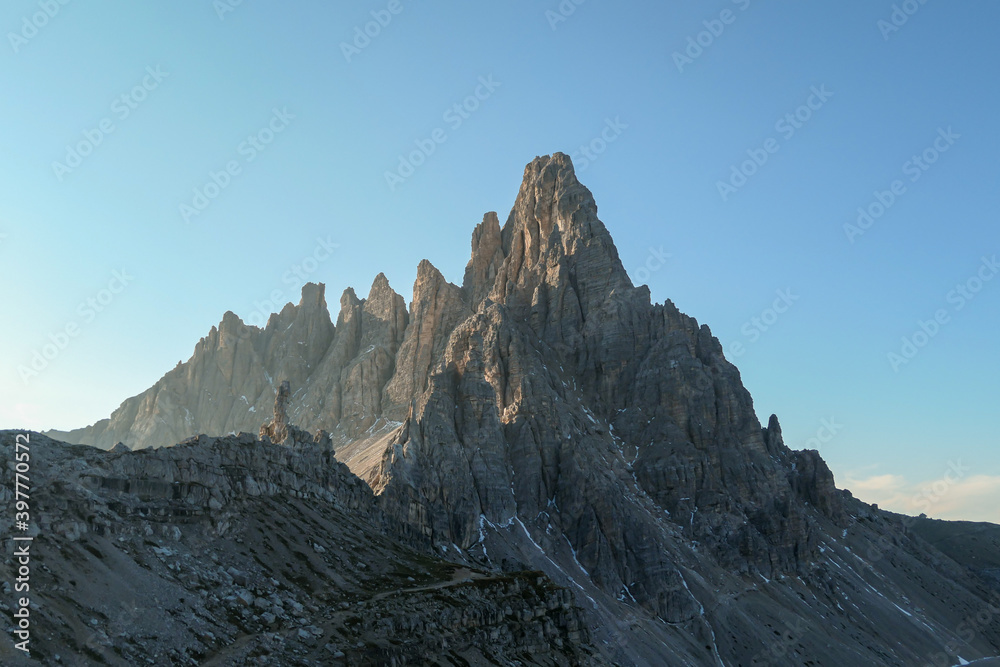 A capture of high and sharp peaks of Frankfurter Wuerstel in Dolomites, Italy during the early morning.  Lots of lose stones and pebbles. Raw and desolated landscape. Daybreak. Serenity and calmness.
