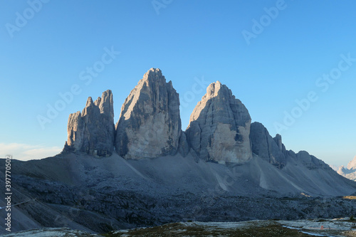 Golden hour in the Tre Cime di Lavaredo (Drei Zinnen) in Italian Dolomites. The mountains are reflecting golden sunrays. There is a lot of landslides and lose stones around. Natural wonder. Sunset © Chris