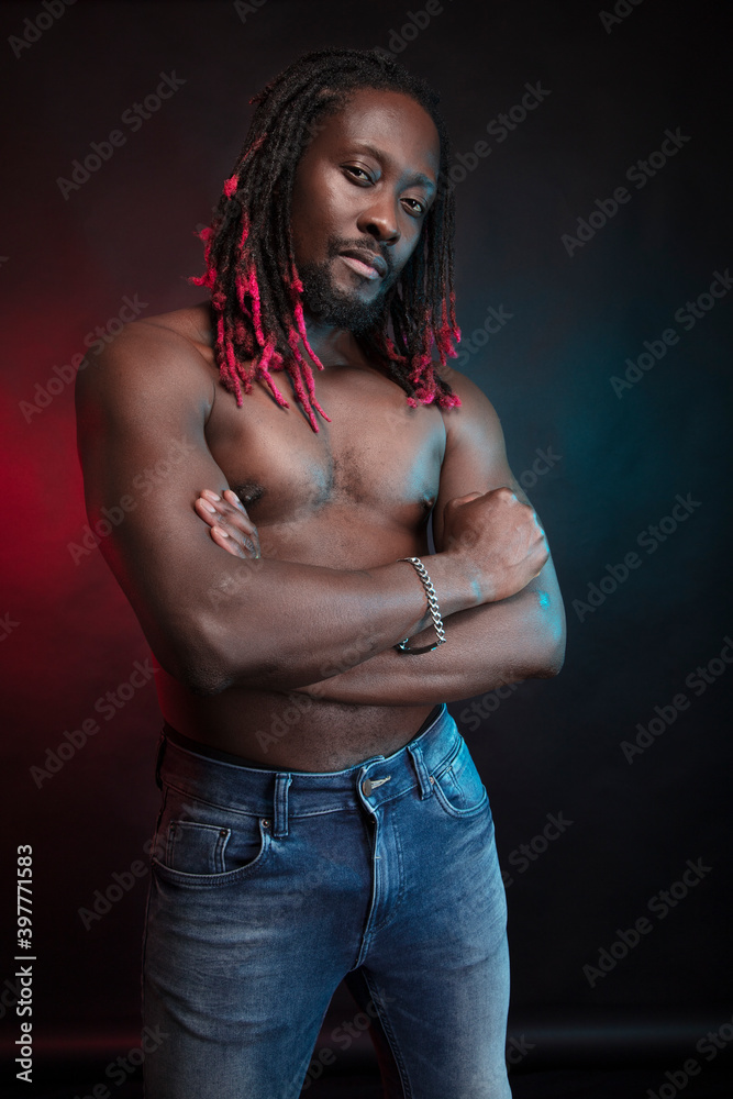 Athletic, courageous black man with a naked torso. Hairstyle, African braids. Photo in the studio, black background.