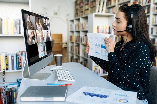 Online video meeting. Computer monitor view with multiracial successful business colleagues, and businesswoman who shows them a graph