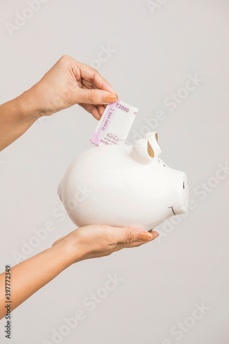 Canvas Print Hand with Indian currency with piggy bank on white.