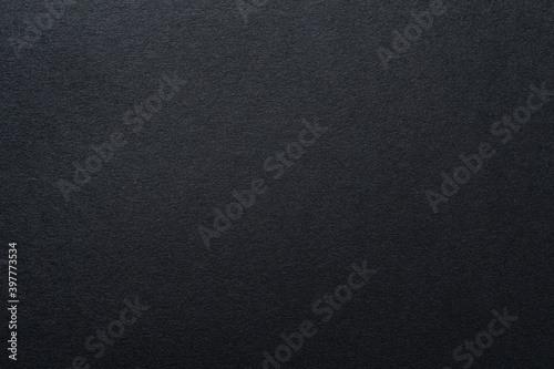 Black paper textured background, close up.