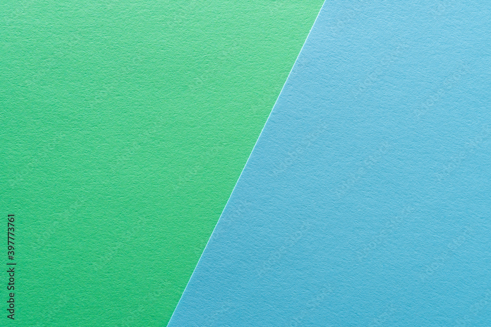 Paper texture background of pastel green and blue colors. Sheets of blank light green and light blue paper with fine texture devided by a sloping border. Paper texture background of pastel green and blue colors. Sheets of blank light green and light blue paper with fine texture devided by a sloping border.