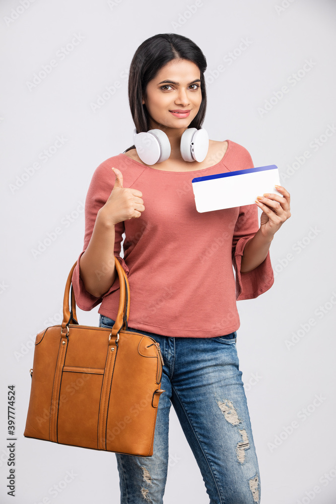 Young beautiful tourist woman holding boarding pass ticket and hand bag on white Young beautiful tourist woman holding boarding pass ticket and hand bag on white